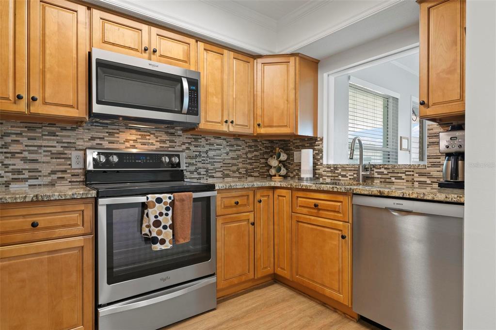 A kitchen with wood cabinets, stainless steel appliances, and a mosaic tile backsplash — 1040 COCKRILL STREET, VENICE, FL