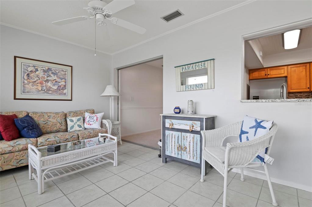 A living room features tile flooring, a wicker sofa and chair, and a kitchen pass-through — 1040 COCKRILL STREET, VENICE, FL