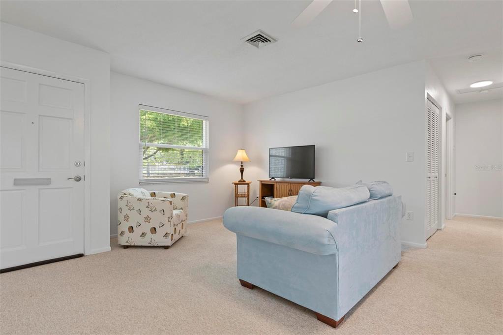 A living room features a light blue sofa, a patterned armchair, and beige carpeting — 1040 COCKRILL STREET, VENICE, FL