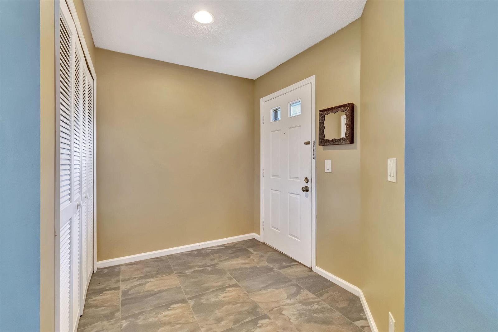 An entryway features a white front door, a louvered closet, and gray tile flooring — 5869 Parkwalk Drive, Boynton Beach FL 33472, BOYNTON BEACH, FL