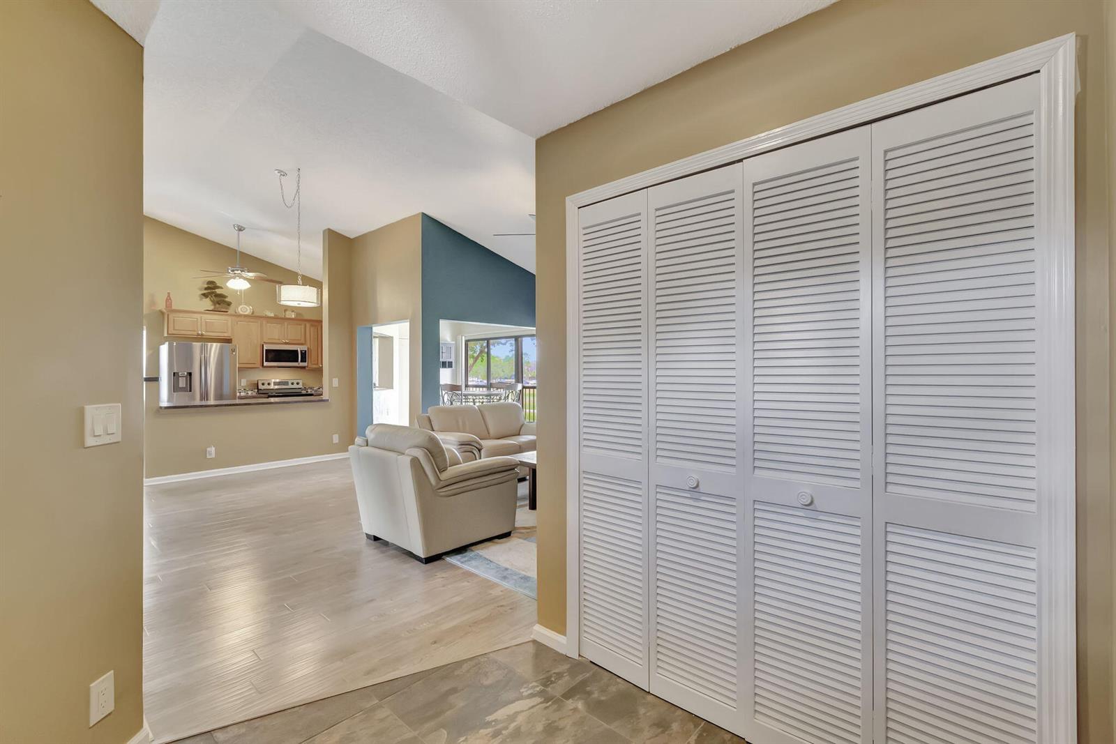 A view from a tiled entryway looking toward a living room with white louvered closets — 5869 Parkwalk Drive, Boynton Beach FL 33472, BOYNTON BEACH, FL