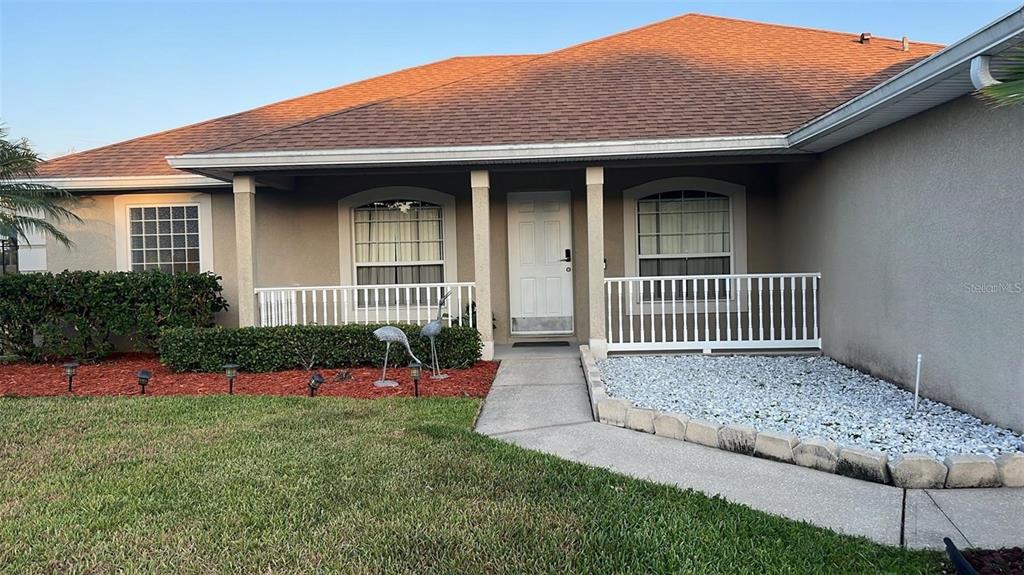 The exterior of a single-story house features a covered porch, white railings, and landscaping — 3116 KEYSTONE POINTE COURT, ST CLOUD, FL