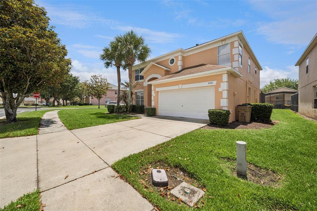 A two-story, peach-colored suburban house with a two-car garage and a concrete driveway — 8550 SUNRISE KEY DRIVE, KISSIMMEE, FL