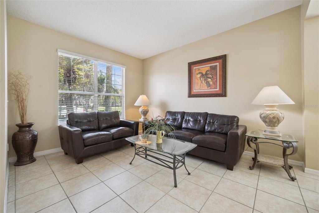 A living room features two dark leather sofas, a glass coffee table, and tile flooring — 8550 SUNRISE KEY DRIVE, KISSIMMEE, FL