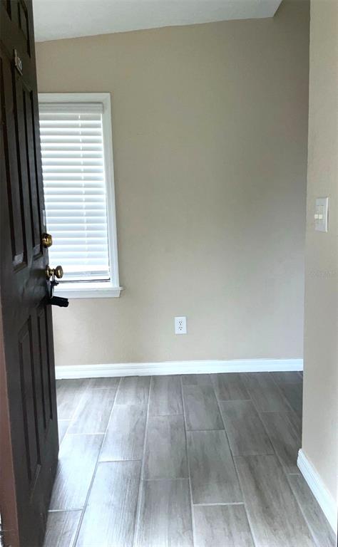 An entryway features a dark door, light-colored walls, and gray wood-look tile flooring — 3014 ANTIQUE OAKS CIRCLE UNIT 120, WINTER PARK, FL