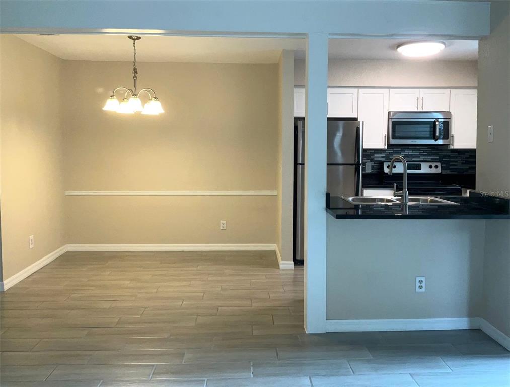 A dining area with light wood-look flooring opens into a kitchen with white cabinets — 3014 ANTIQUE OAKS CIRCLE UNIT 120, WINTER PARK, FL