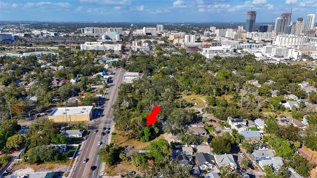 An aerial view shows a wooded lot marked by a red arrow near a city — 1118 S DR MARTIN LUTHER KING JR STREET S, ST PETERSBURG, FL