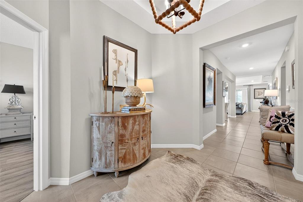 A foyer features a wooden cabinet, a cowhide rug, and a hallway leading to living areas — 4709 NW 51ST COURT, OCALA, FL