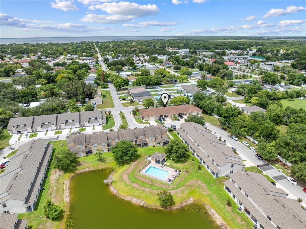 An aerial view shows a residential complex with townhomes, a swimming pool, and a pond — 1779 BARTON TOWNE CIRCLE, ST CLOUD, FL