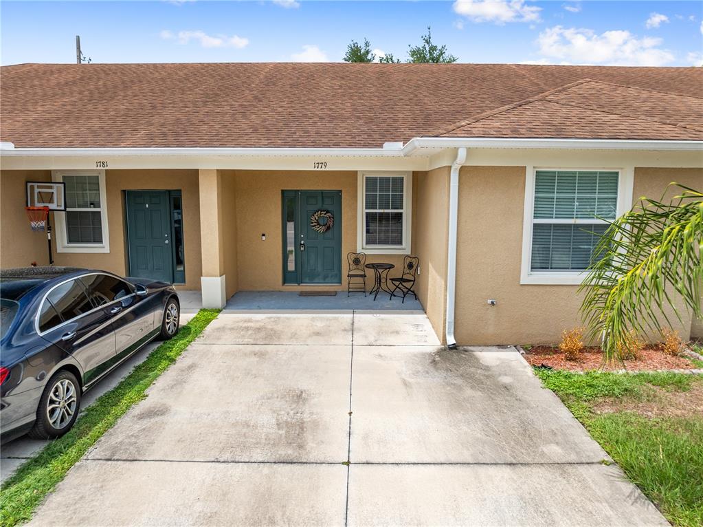 The exterior view shows a tan duplex with a concrete driveway and two front doors — 1779 BARTON TOWNE CIRCLE, ST CLOUD, FL
