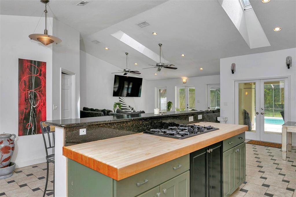 A kitchen island with a butcher block countertop and gas cooktop overlooks a living area — 3585 SE 55TH COURT, OCALA, FL