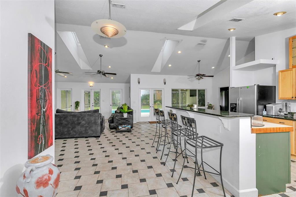A spacious open-concept living area features a kitchen island with bar stools and tiled floors — 3585 SE 55TH COURT, OCALA, FL