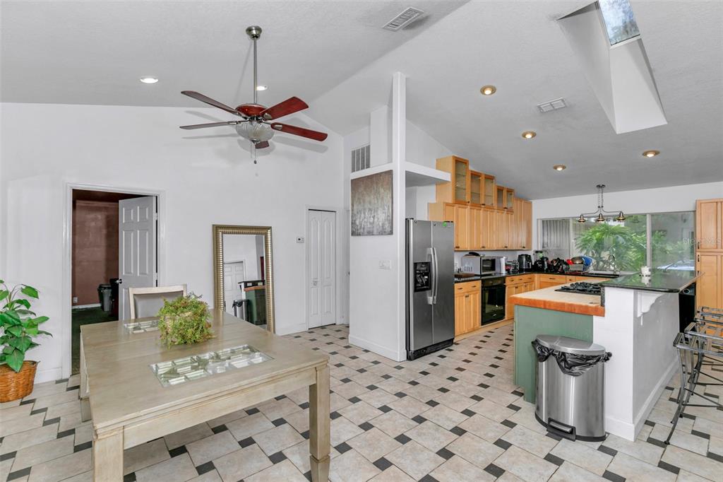 A kitchen and dining area with tile floors, wooden cabinets, and a vaulted ceiling — 3585 SE 55TH COURT, OCALA, FL