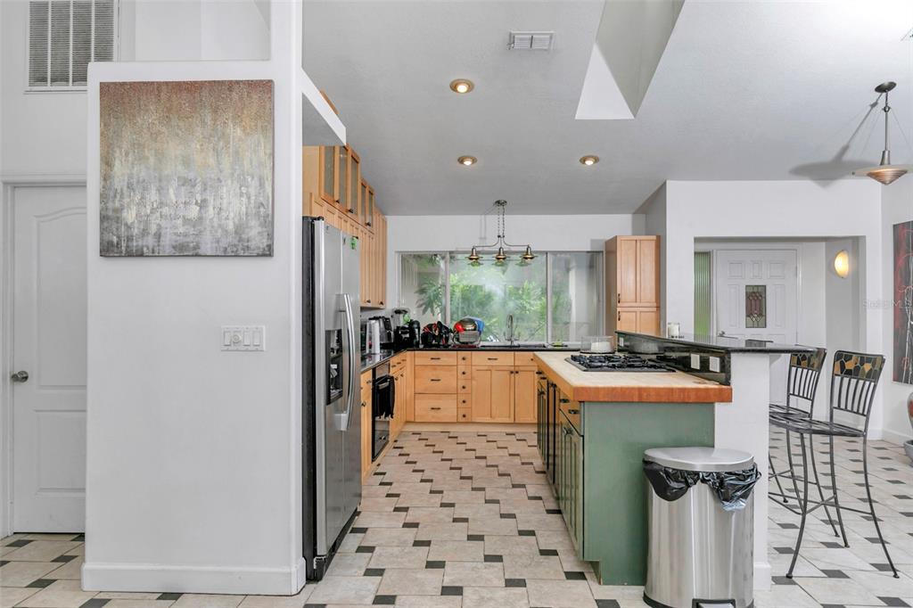 A kitchen features light wood cabinets, a green island with a wood countertop, and tile flooring — 3585 SE 55TH COURT, OCALA, FL