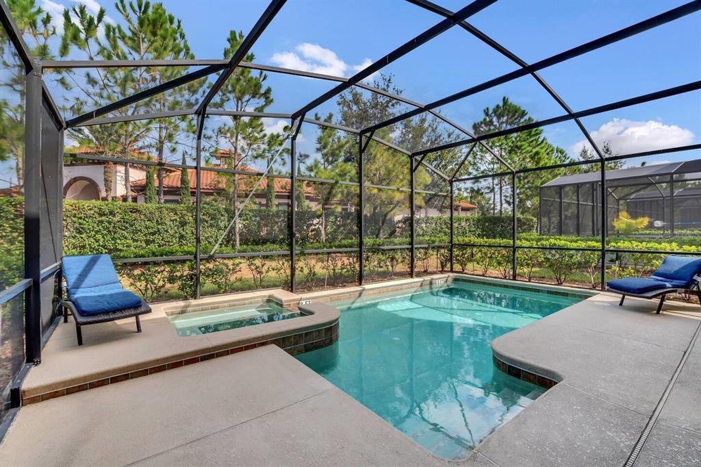 A screened-in swimming pool and spa with lounge chairs on a concrete patio — 5504 SOLTERRA CIRCLE, DAVENPORT, FL