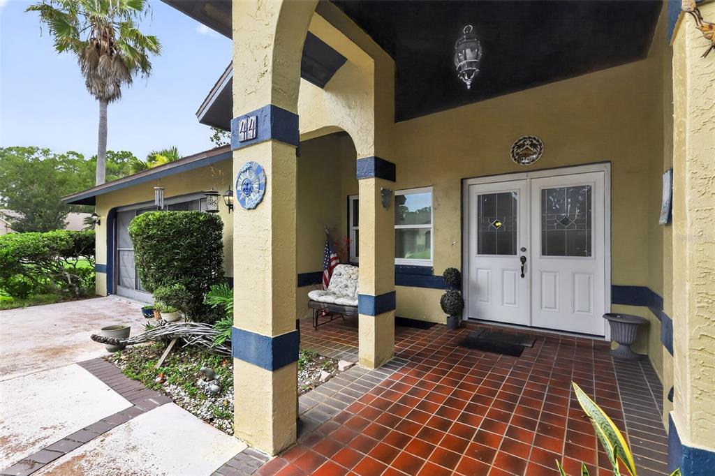 A covered front porch with tiled flooring leads to a white double door entrance — 44 WEDGEWOOD LANE, PALM COAST, FL