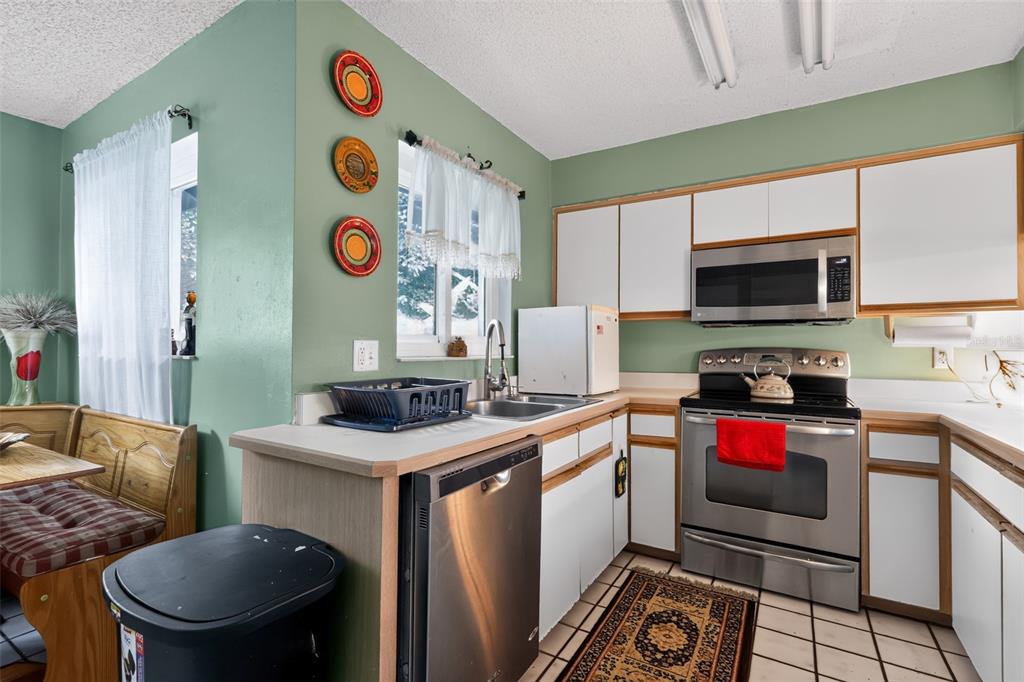 A kitchen features green walls, white cabinets, stainless steel appliances, and a tiled floor — 44 WEDGEWOOD LANE, PALM COAST, FL