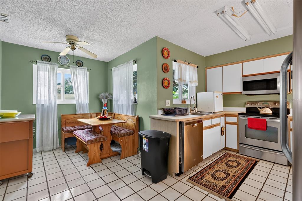 A kitchen with green walls, white cabinets, stainless steel appliances, and a wooden breakfast nook — 44 WEDGEWOOD LANE, PALM COAST, FL