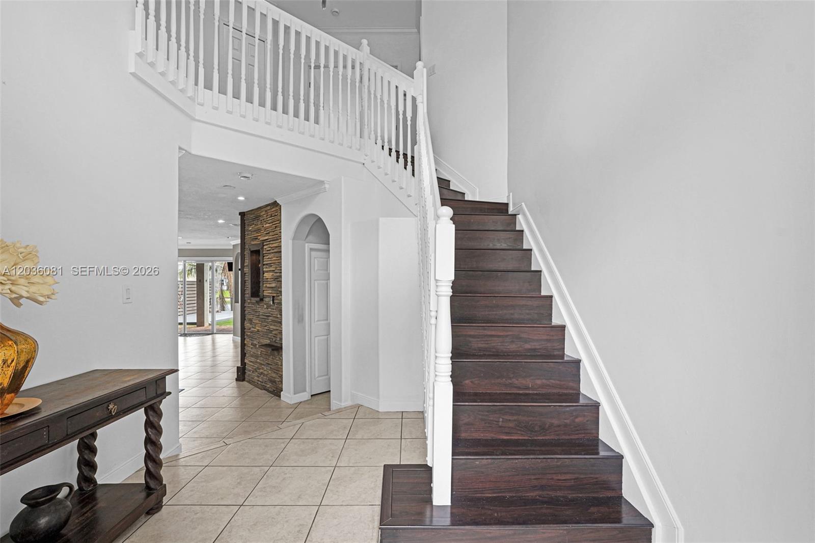 A staircase with dark wood treads and white railings leads to an upper landing — 11258 NW 47th Ln, Doral FL 33178, DORAL, FL