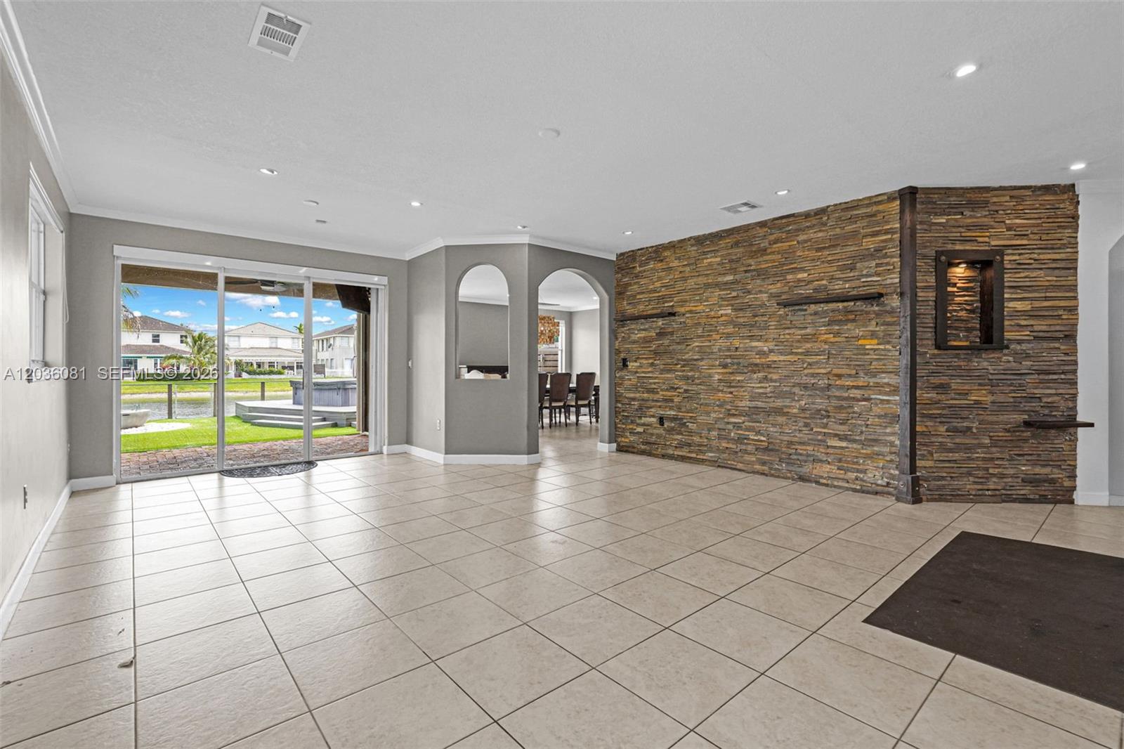 A spacious living area features large tile floors, a stone accent wall, and sliding glass doors — 11258 NW 47th Ln, Doral FL 33178, DORAL, FL