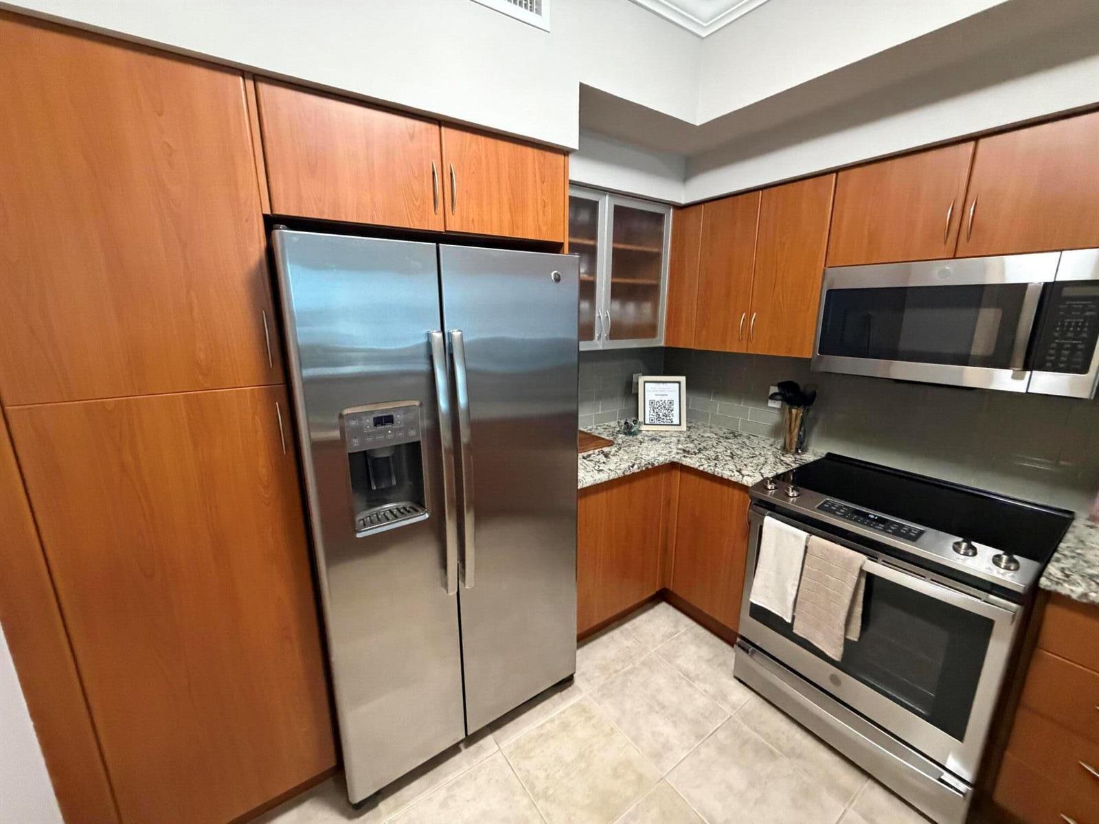 A kitchen features stainless steel appliances, wood cabinets, and granite countertops — 804 E Windward Way # 618, Lantana FL 33462, LANTANA, FL