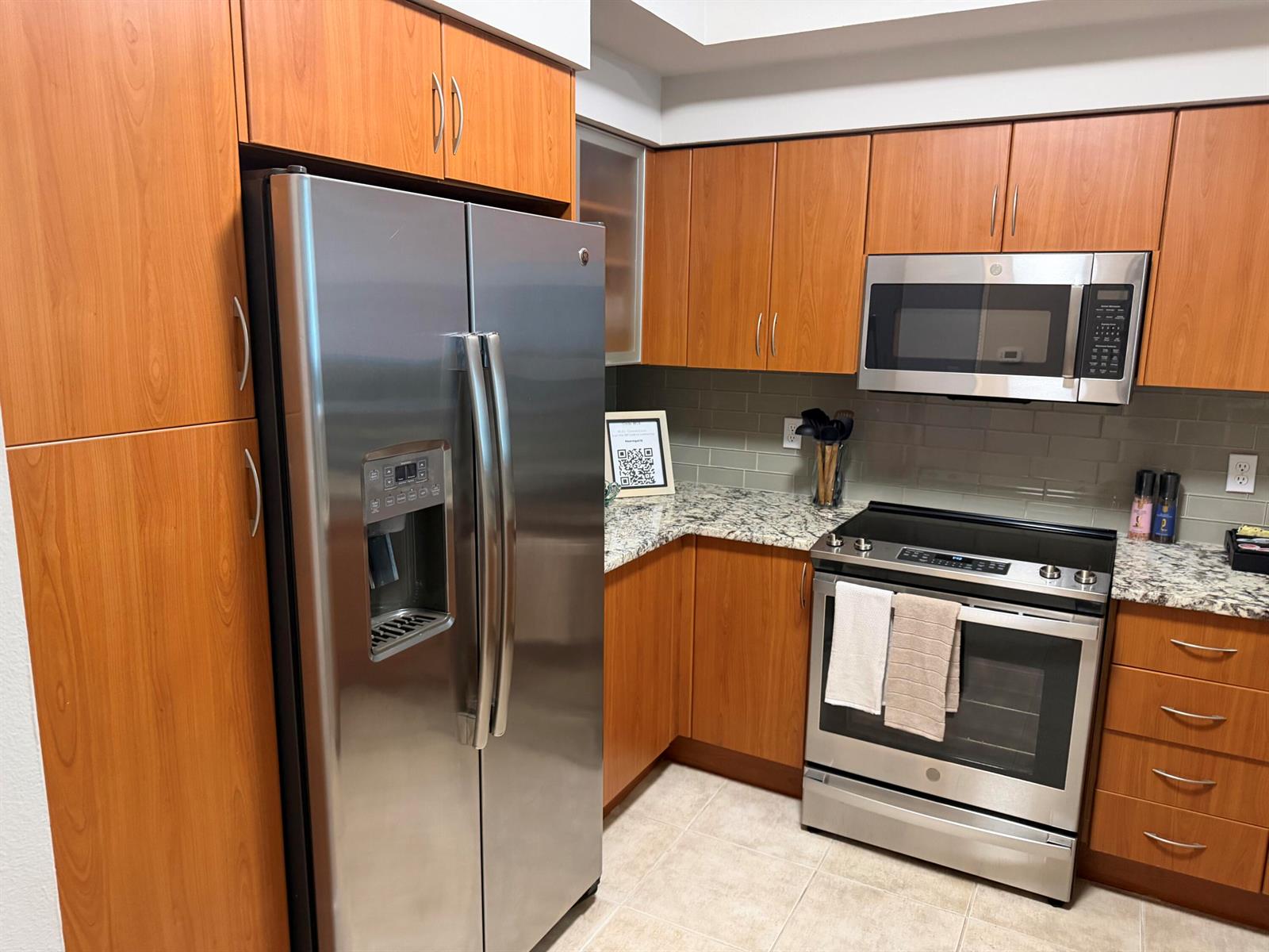 A kitchen features wood cabinets, stainless steel appliances, and granite countertops with a tile backsplash — 804 E Windward Way # 618, Lantana FL 33462, LANTANA, FL
