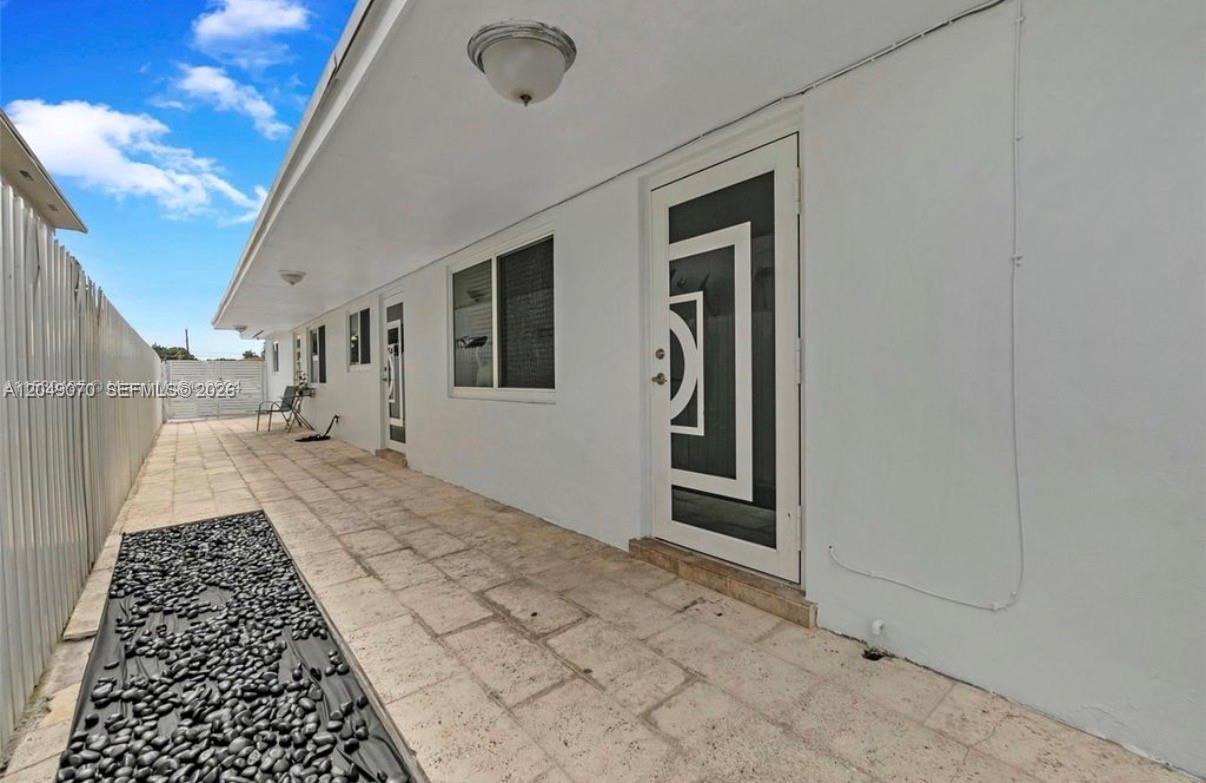 A paved walkway runs along the side of a white building with several doors — 329 W 18th St, Hialeah FL 33010, HIALEAH, FL