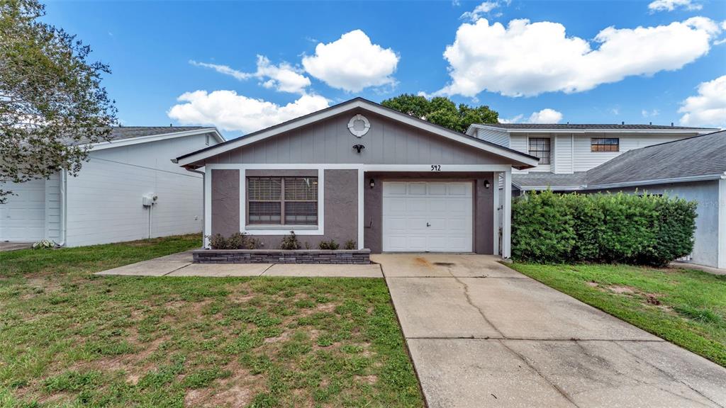 A single-story house with a gray stucco facade, a white garage door, and a driveway — 542 LAKE DEXTER BOULEVARD, WINTER HAVEN, FL