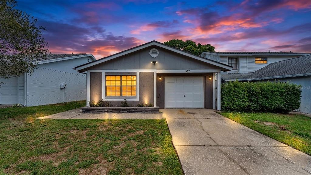 A single-story house with a gray exterior, a white garage door, and a concrete driveway — 542 LAKE DEXTER BOULEVARD, WINTER HAVEN, FL