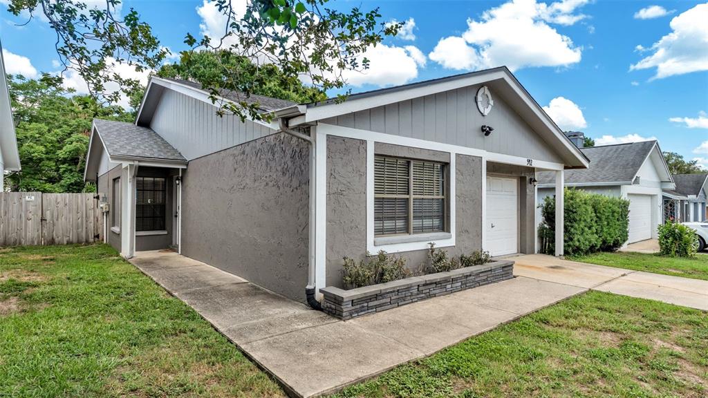 A single-story house with gray stucco and vertical siding, a stone planter, and a driveway — 542 LAKE DEXTER BOULEVARD, WINTER HAVEN, FL