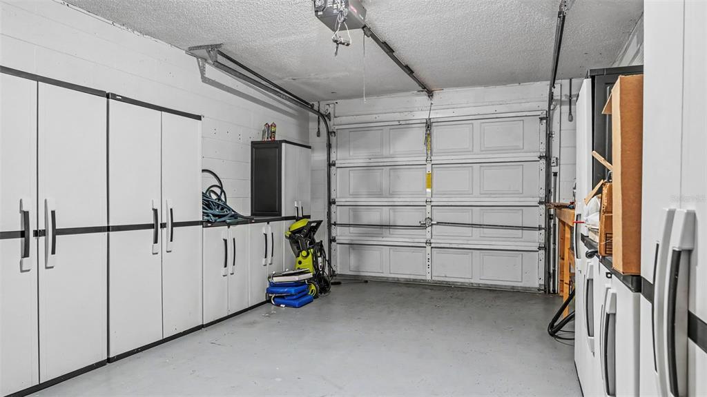A garage with white storage cabinets, a concrete floor, and a white sectional garage door — 542 LAKE DEXTER BOULEVARD, WINTER HAVEN, FL