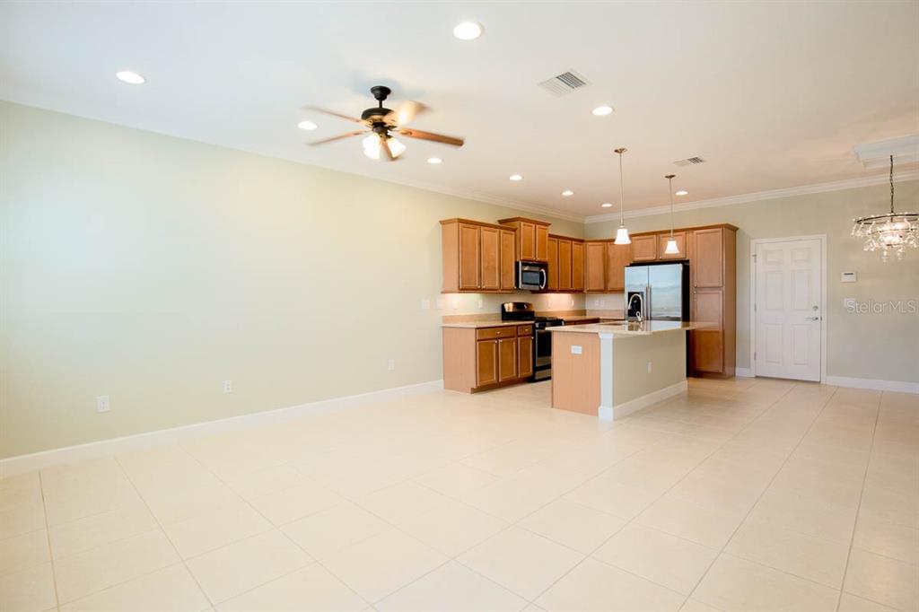 A kitchen with wood cabinets and an island opens into a large, tiled living area — 16856 DORMAN ROAD, LITHIA, FL