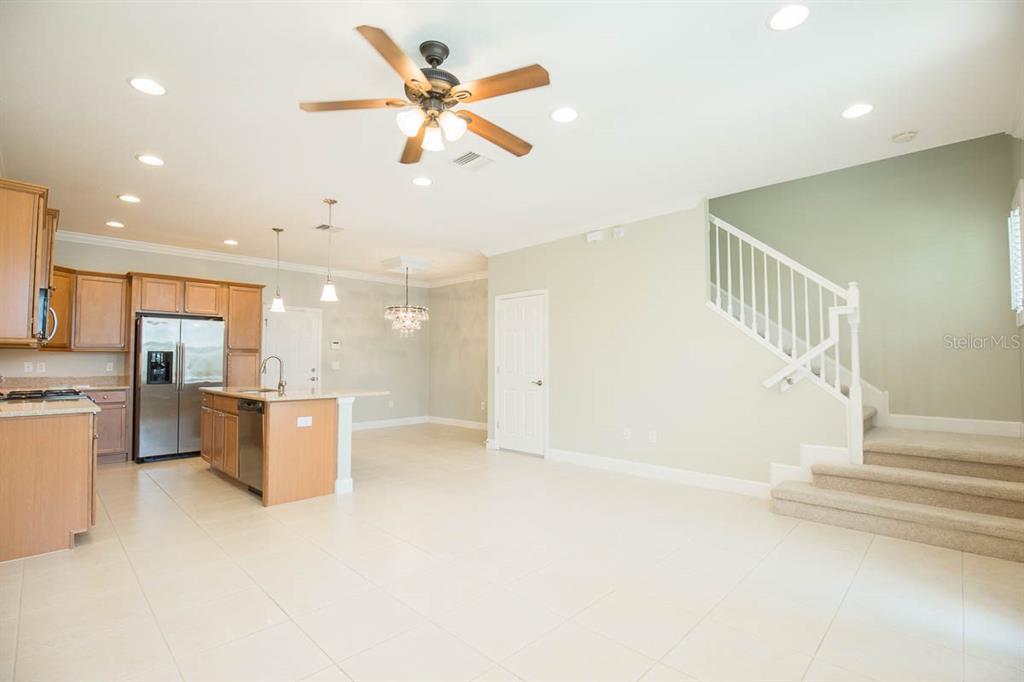 An open-concept kitchen and living area features light tile flooring, wood cabinetry, and a staircase — 16856 DORMAN ROAD, LITHIA, FL