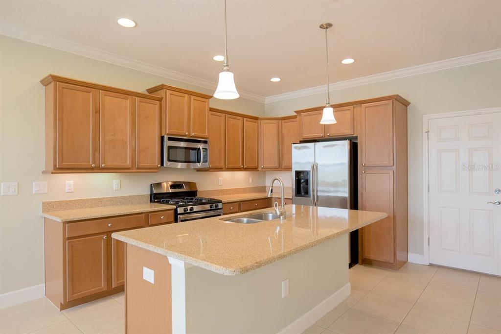 A kitchen features light wood cabinets, granite countertops, a center island, and stainless steel appliances — 16856 DORMAN ROAD, LITHIA, FL