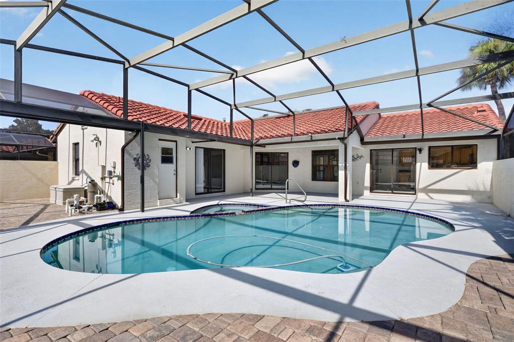 A screened-in patio features a swimming pool with a spa and red tile roof — 8052 S CADIZ COURT, ORLANDO, FL