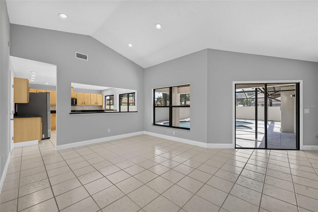 A bright, tiled living area features vaulted ceilings, a kitchen pass-through, and sliding glass doors — 8052 S CADIZ COURT, ORLANDO, FL