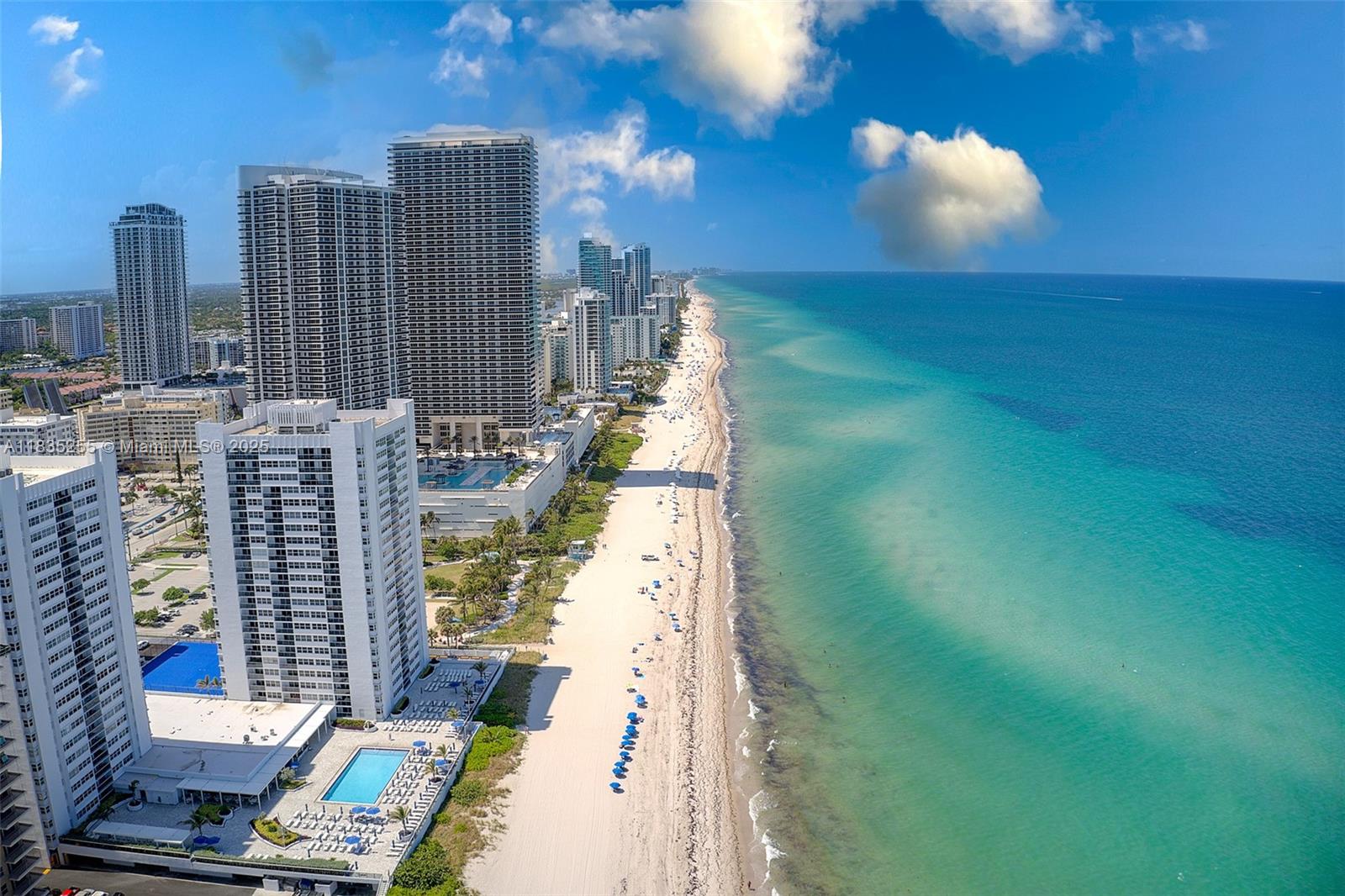 An aerial view shows high-rise residential buildings along a sandy beach and the ocean — 1945 S Ocean Dr # 901, Hallandale Beach FL 33009, HALLANDALE BEACH, FL