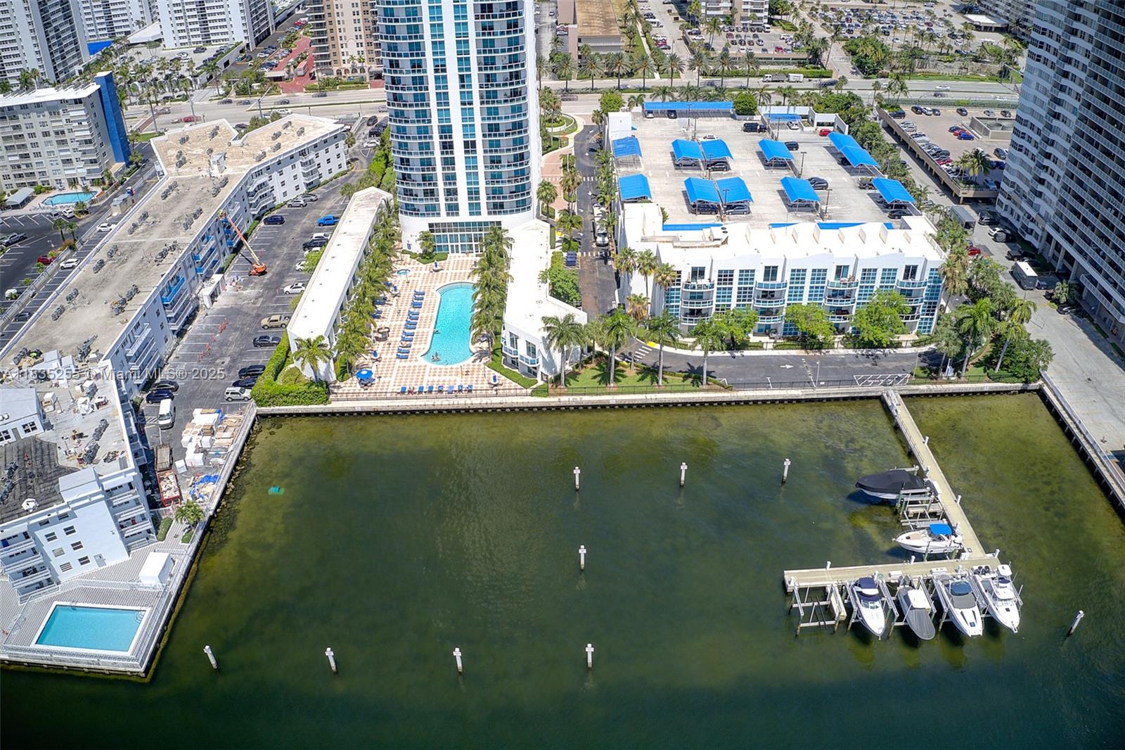 An aerial view shows a waterfront residential complex with a pool, parking, and boat slips — 1945 S Ocean Dr # 901, Hallandale Beach FL 33009, HALLANDALE BEACH, FL