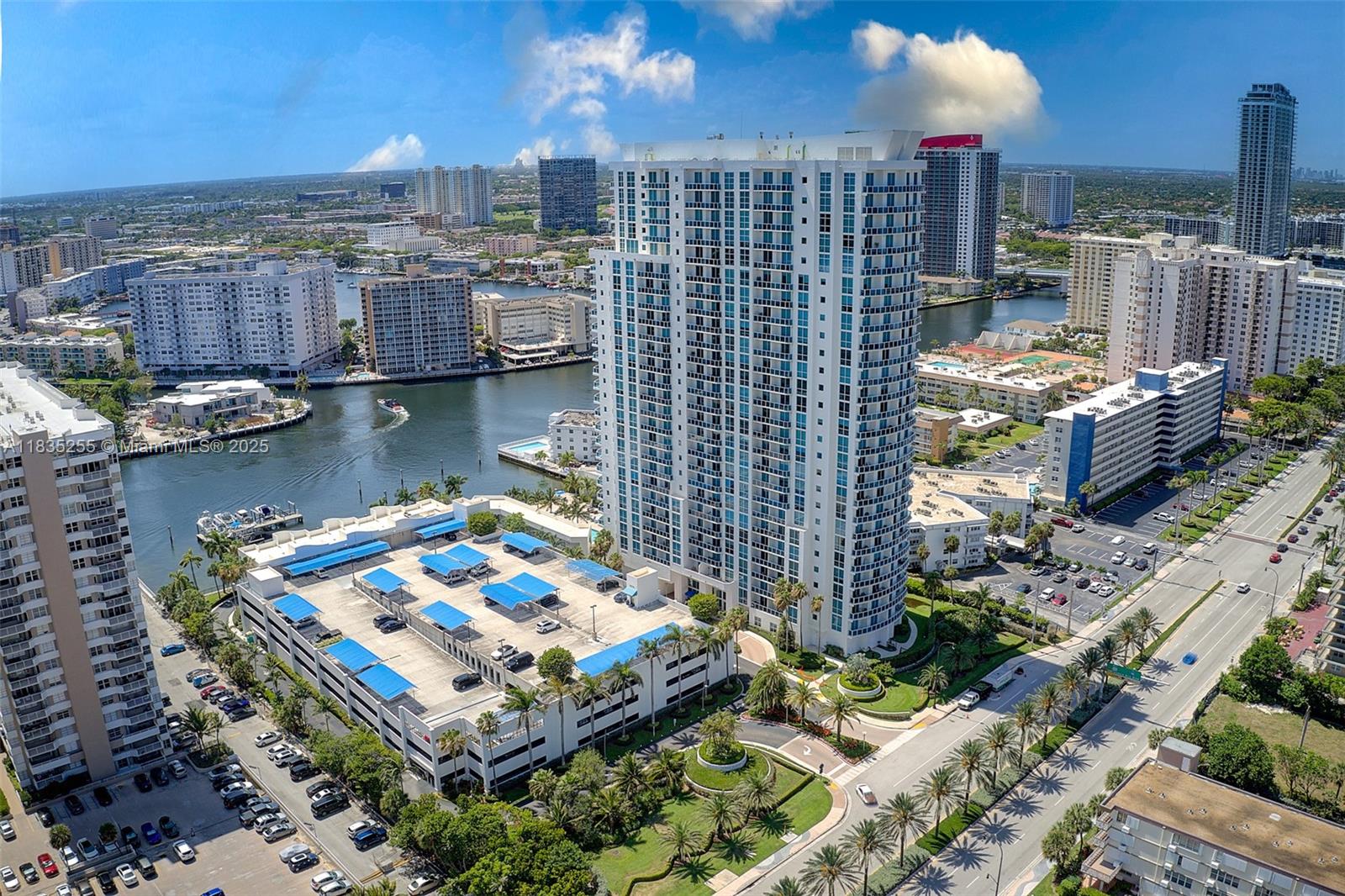 An aerial view shows a tall residential tower, a parking garage, and a waterway — 1945 S Ocean Dr # 901, Hallandale Beach FL 33009, HALLANDALE BEACH, FL