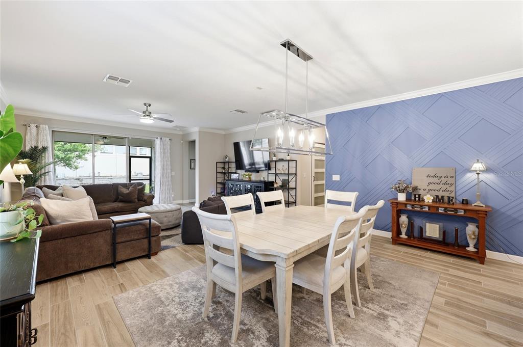 A dining area with a white table and chairs sits before a blue accent wall — 31553 CANNON RUSH DRIVE, SAN ANTONIO, FL