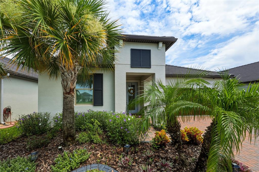A single-story house exterior features a palm tree, landscaped garden, and a paved driveway — 31553 CANNON RUSH DRIVE, SAN ANTONIO, FL