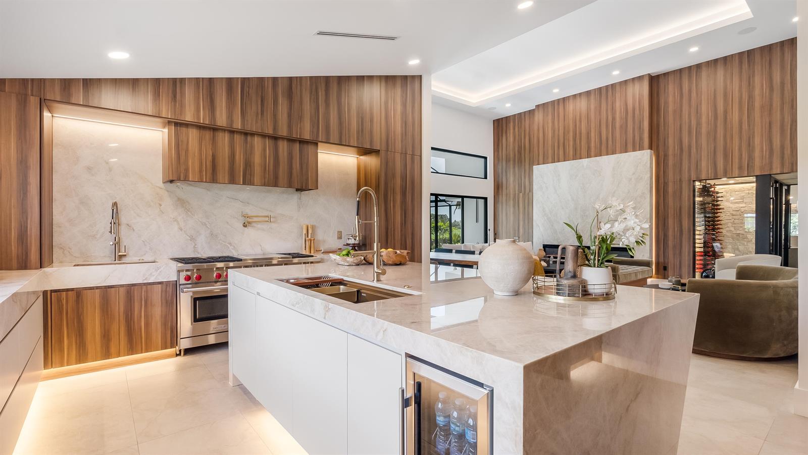 A modern kitchen features wood cabinetry, marble countertops, a large island, and stainless steel appliances — 10290 Silver Lake Drive, Boca Raton FL 33428, BOCA RATON, FL