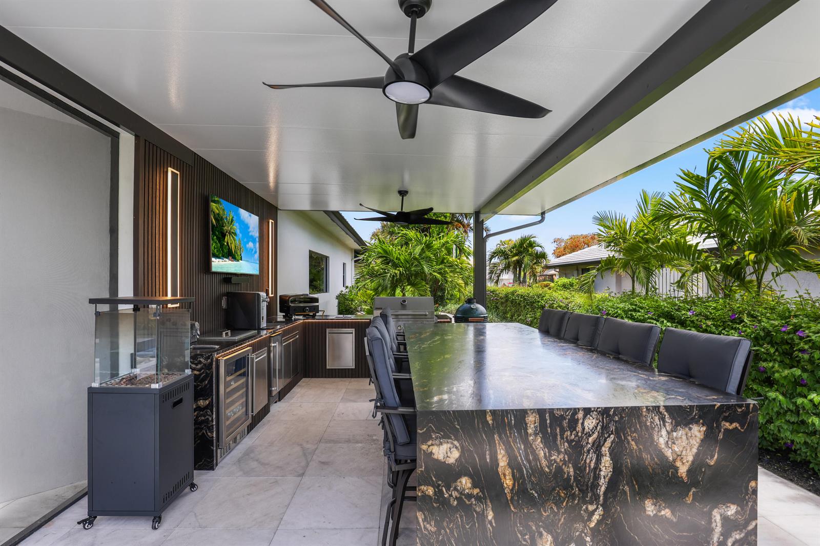 An outdoor kitchen features a large stone island, bar seating, and a ceiling fan — 10290 Silver Lake Drive, Boca Raton FL 33428, BOCA RATON, FL