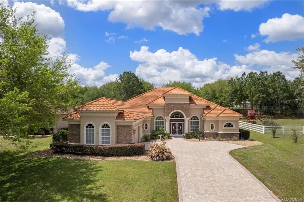 A single-story house with a terracotta tile roof and a stone-accented arched entryway — 291 S PALADINN CIRCLE, INVERNESS, FL