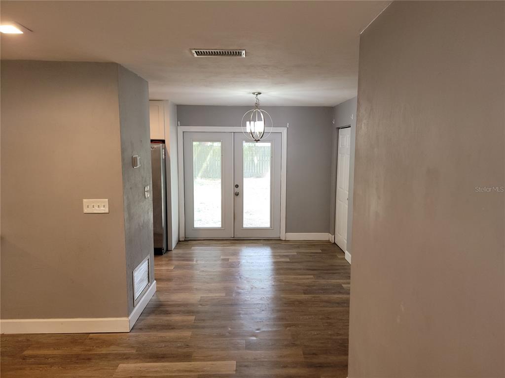 A dining area features wood-look flooring, gray walls, a modern chandelier, and double glass doors — 26424 SW 1 AVENUE, NEWBERRY, FL