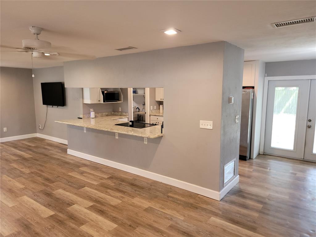 A kitchen features a granite breakfast bar, gray walls, and light wood-look flooring — 26424 SW 1 AVENUE, NEWBERRY, FL