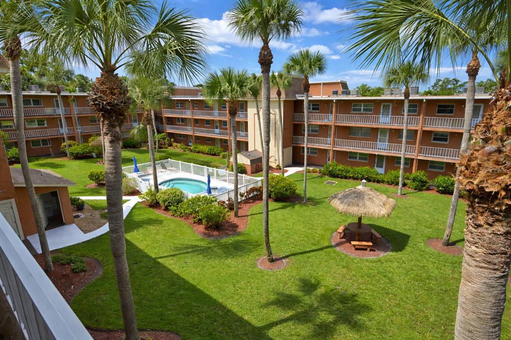 An elevated view of an apartment complex courtyard featuring a swimming pool and palm trees — 12760 INDIAN ROCKS ROAD UNIT 573, LARGO, FL