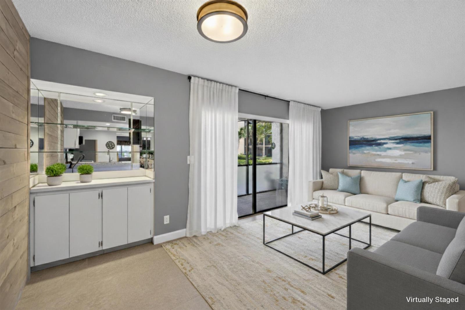 A living room features gray walls, a white cabinet with a mirrored backsplash, and sliding doors — 1605 S Us Highway 1 # D105, Jupiter FL 33477, JUPITER, FL