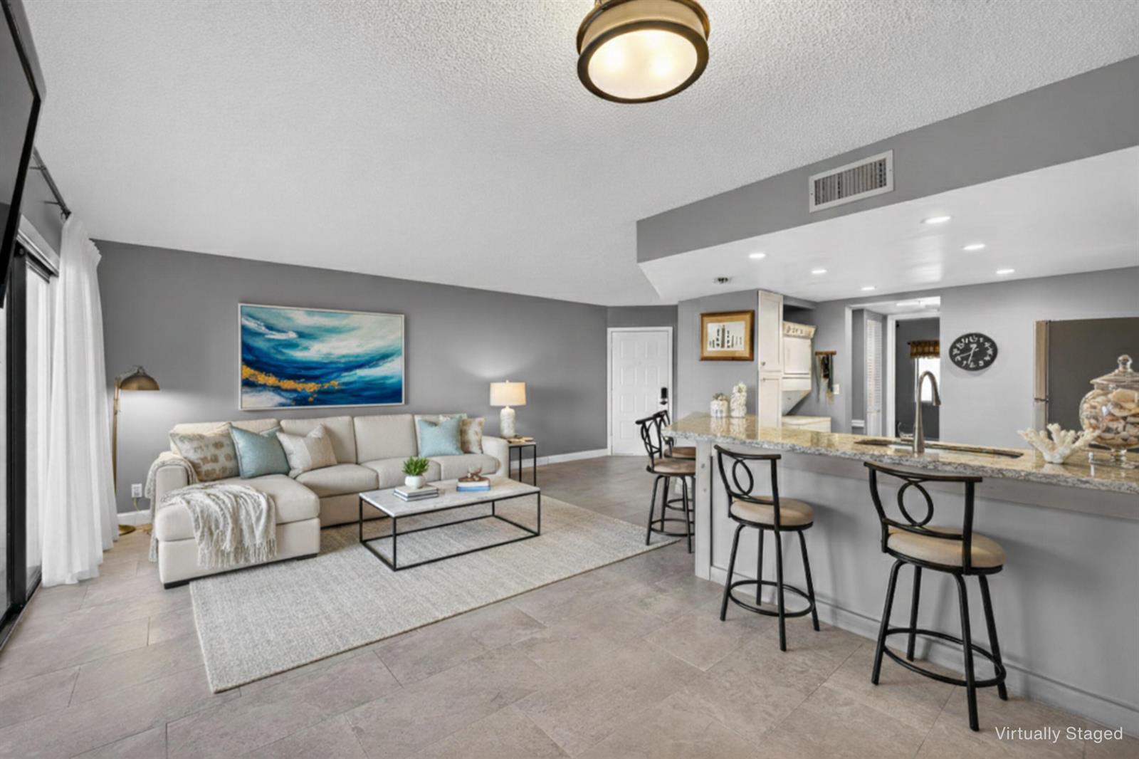 A living room with a sectional sofa and a kitchen breakfast bar with stools — 1605 S Us Highway 1 # D105, Jupiter FL 33477, JUPITER, FL