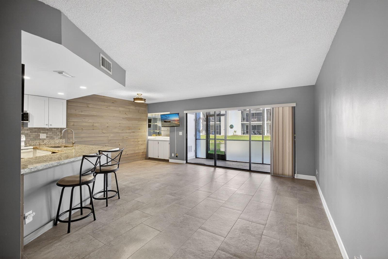 A kitchen with a breakfast bar and wood-paneled wall opens into a tiled living area — 1605 S Us Highway 1 # D105, Jupiter FL 33477, JUPITER, FL